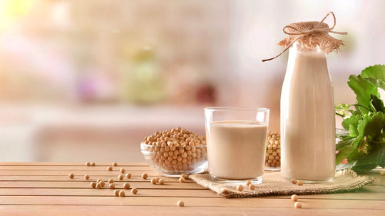 Fresh soymilk in a glass and jug and fresh soybeans in a glass bowl